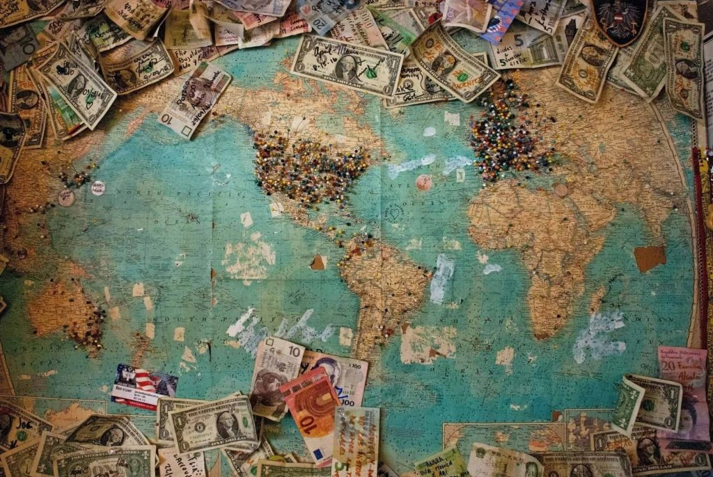 global map with currency strewn about it signifying expats money in different countries as they travel